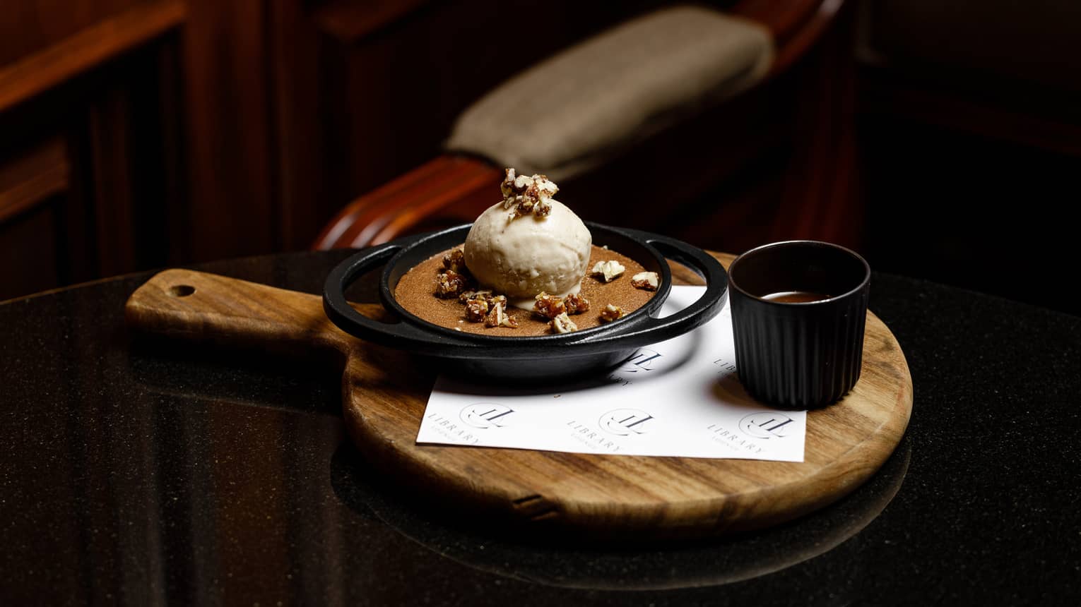 Chocolate cake served in a cast-iron dish with a scoop of banana ice cream on top