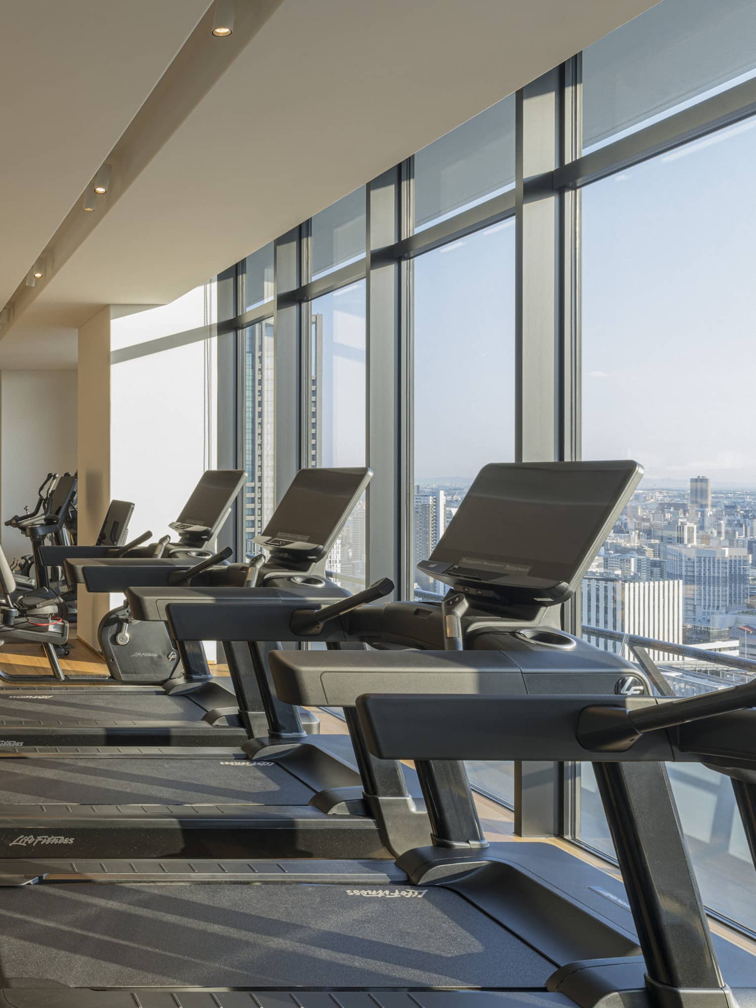 Indoor, light-filled gym at Four Seasons Hotel Suzhou, with a row of treadmills, bikes and other weight training machines