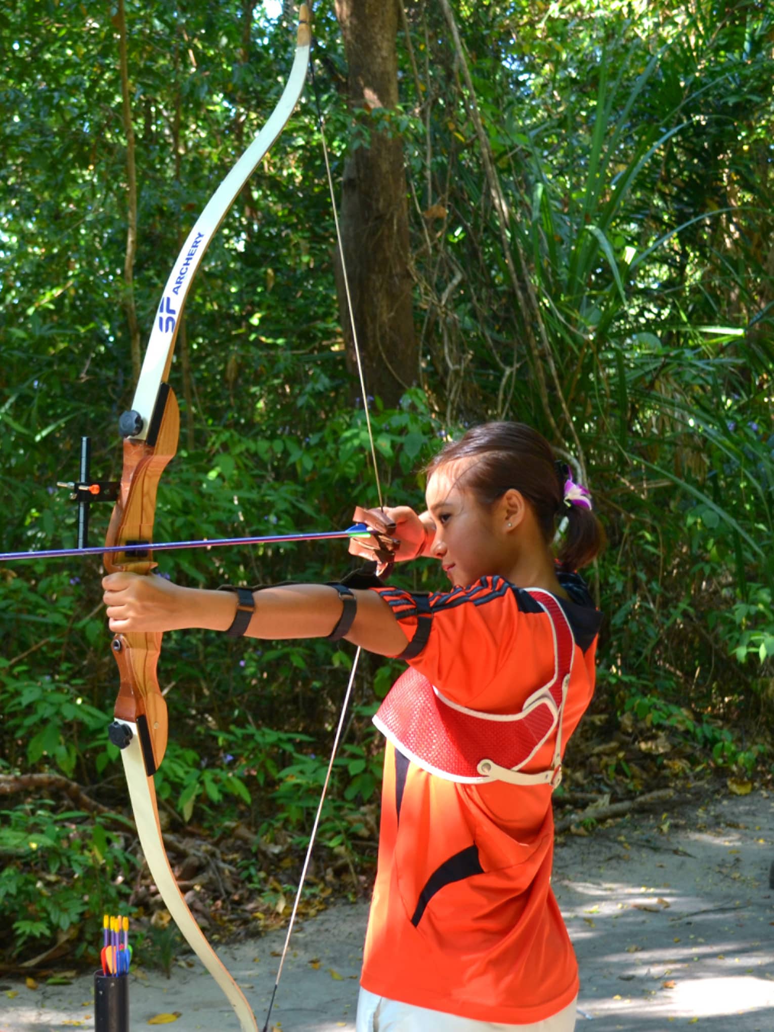 Man and woman stand with archery bow and arrows, prepare to shoot