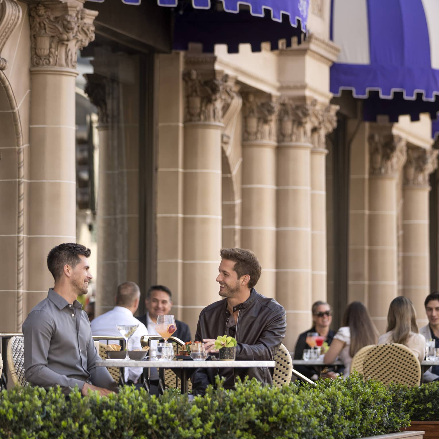 Small groups of people sitting and dining on an outside patio.