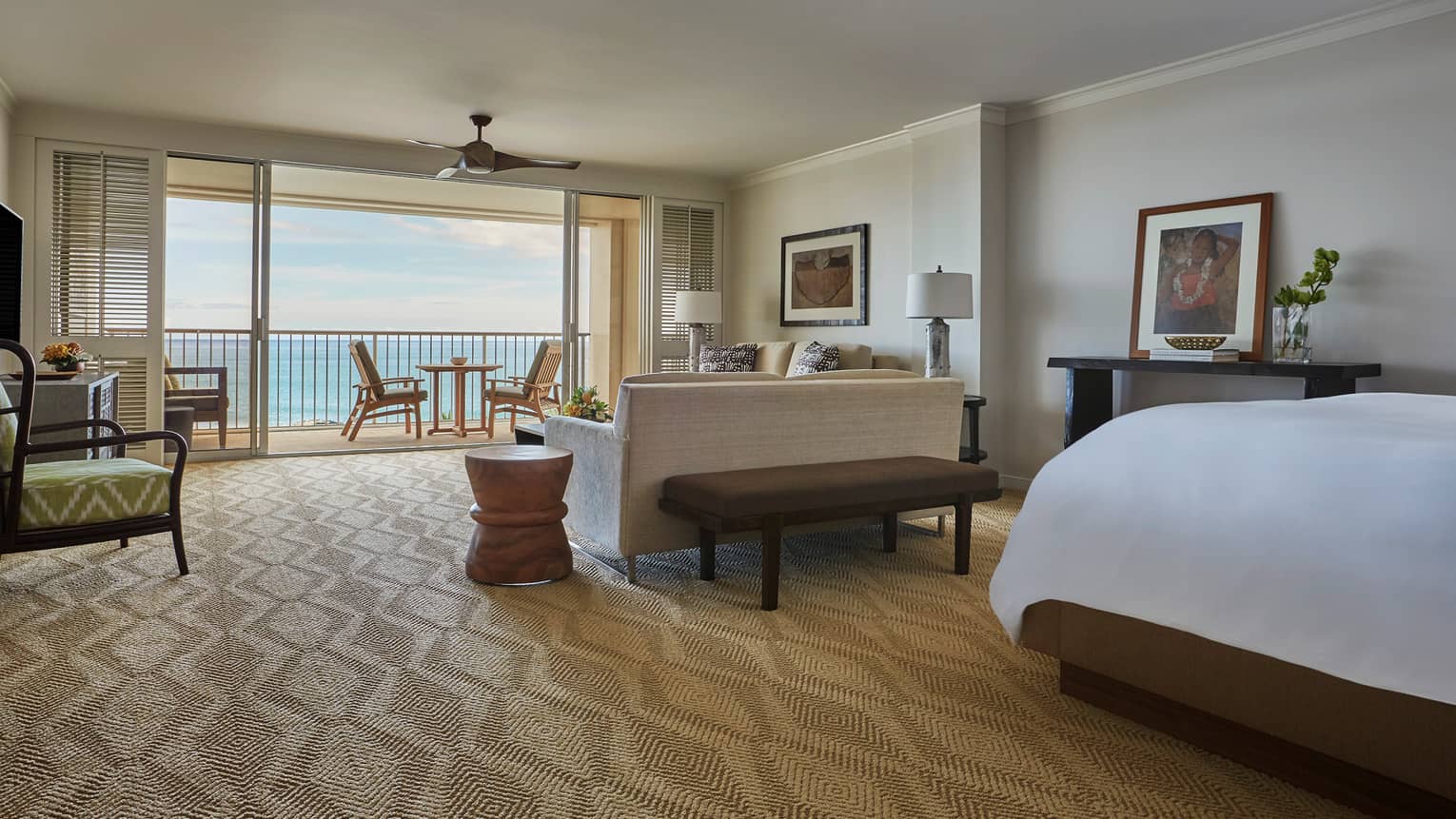 Oceanfront Junior Suite corner of bed behind living room, sofa facing open sliding patio doors