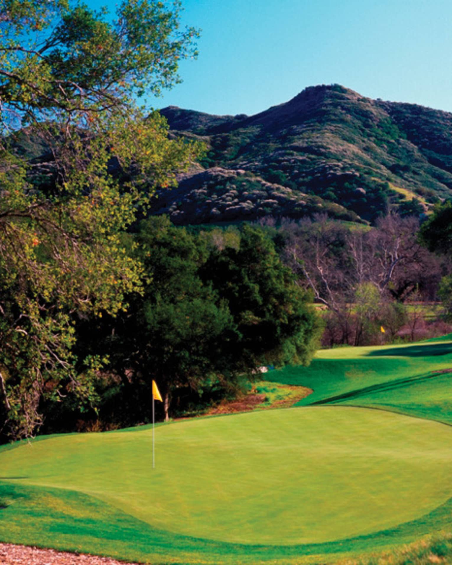 A golf course with a beautiful mountain in the background.