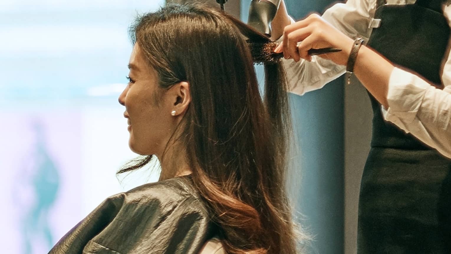 Hair stylist blow dries woman's hair in hotel salon