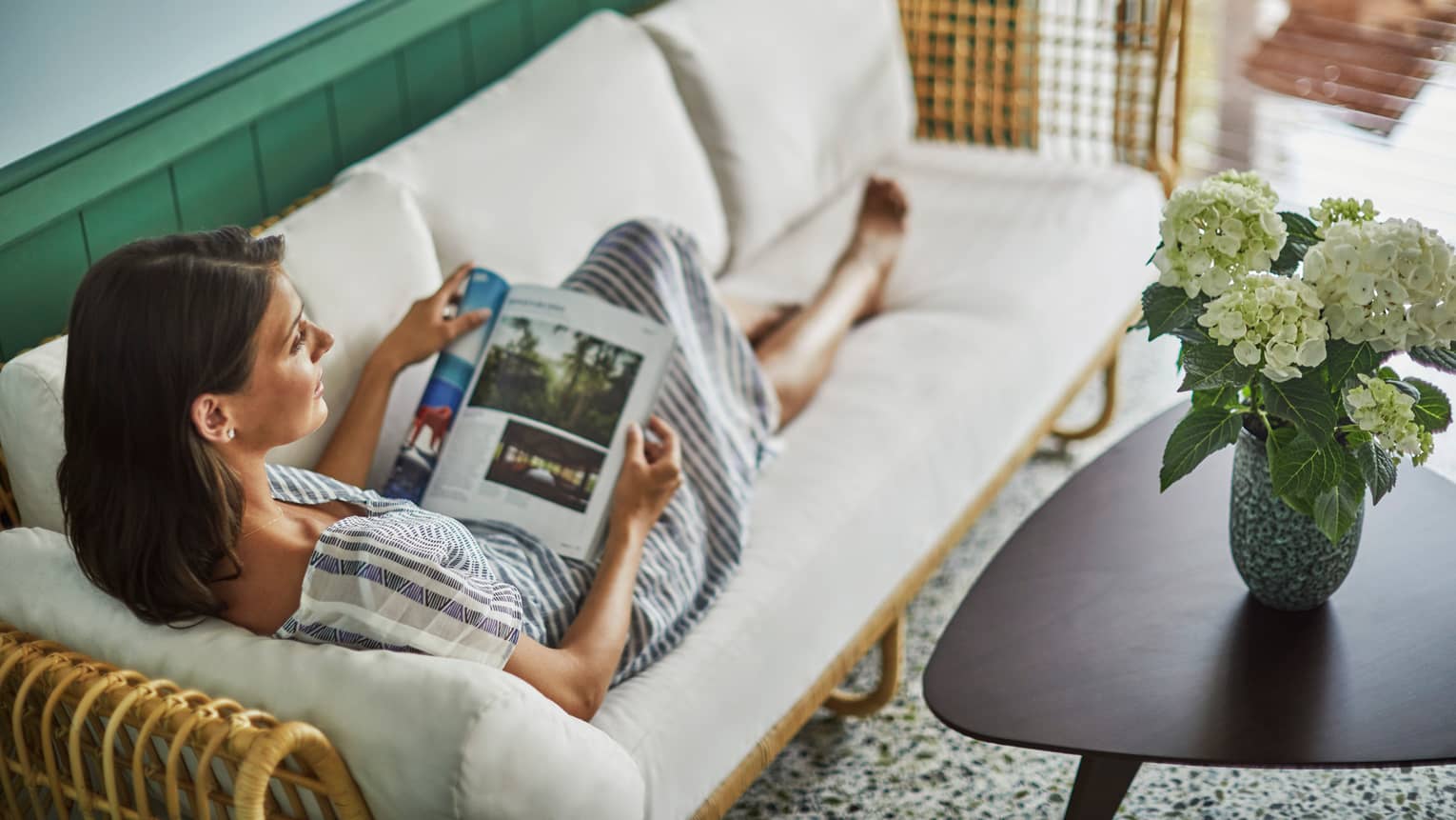 Private spa cabanas offer privacy. Woman stretches out on a sofa, reads magazine
