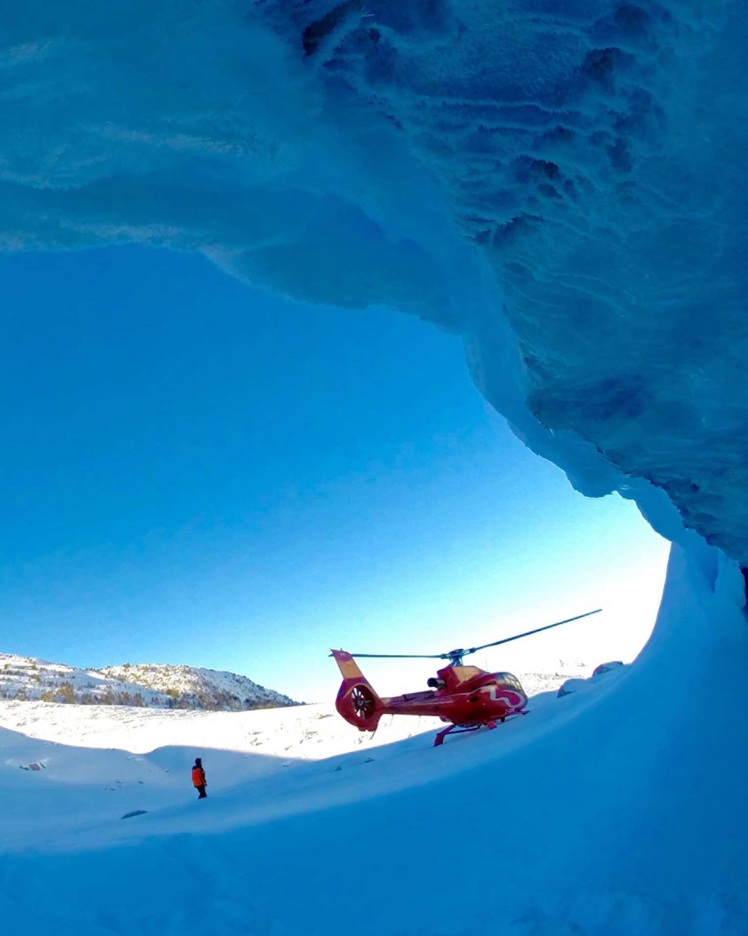 Helicopter against striking blue sky at opening of ice cave