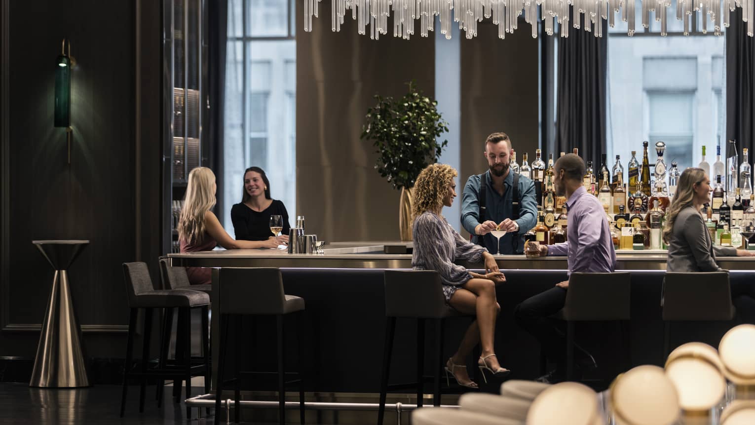 People sitting at a bar conversing and enjoying drinks.