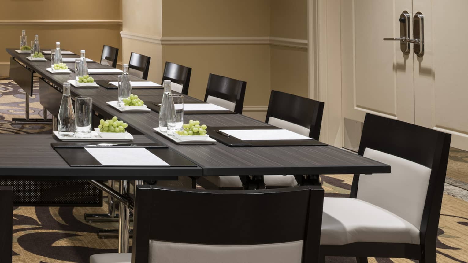 Meeting room with modular boardroom tables lines with white chairs 