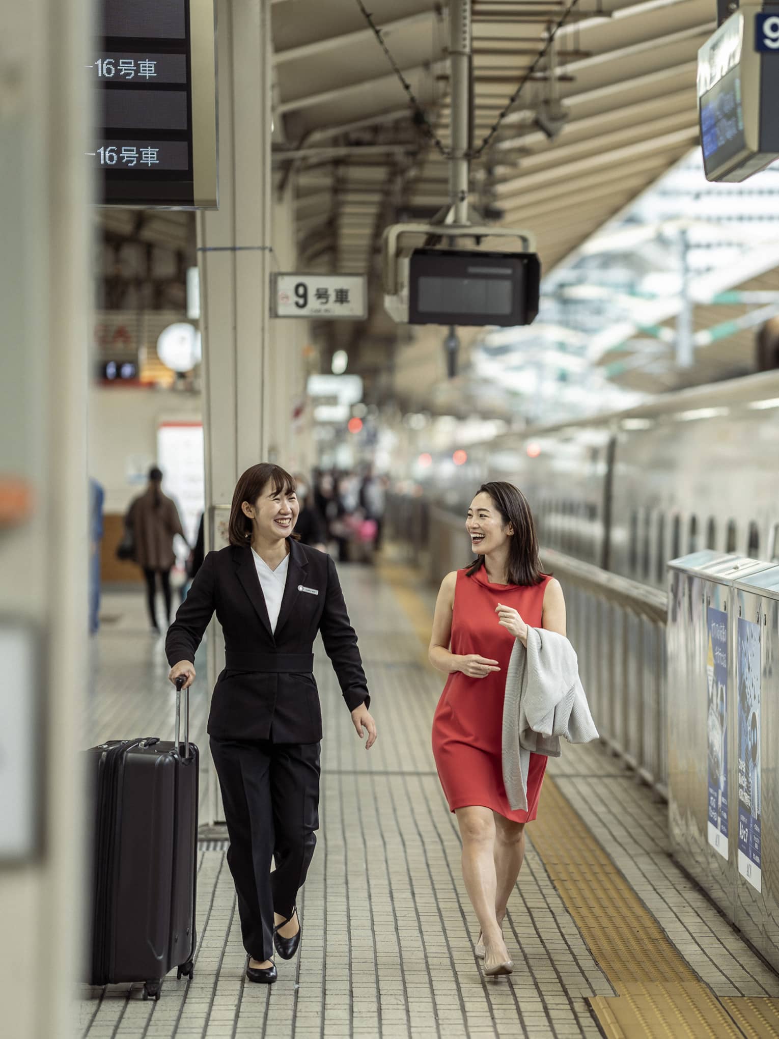 Train station greeter walks with female guest along the train platform