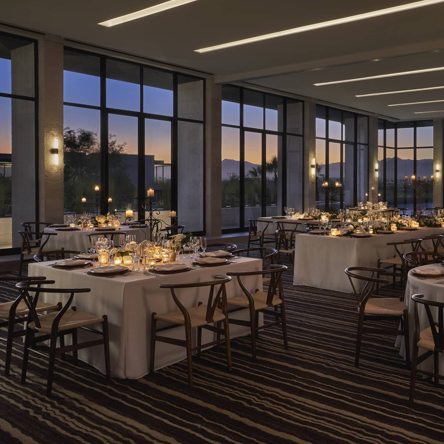 Ballroom with floor-to-ceiling windows and tables with candles.