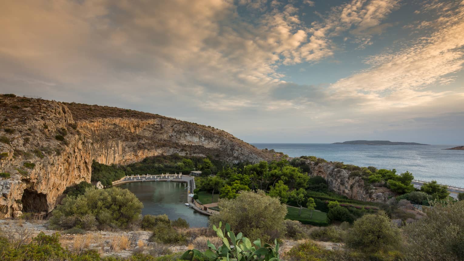View of Vouliagmeni with rocky hill, green trees and shrubs overlooking ocean