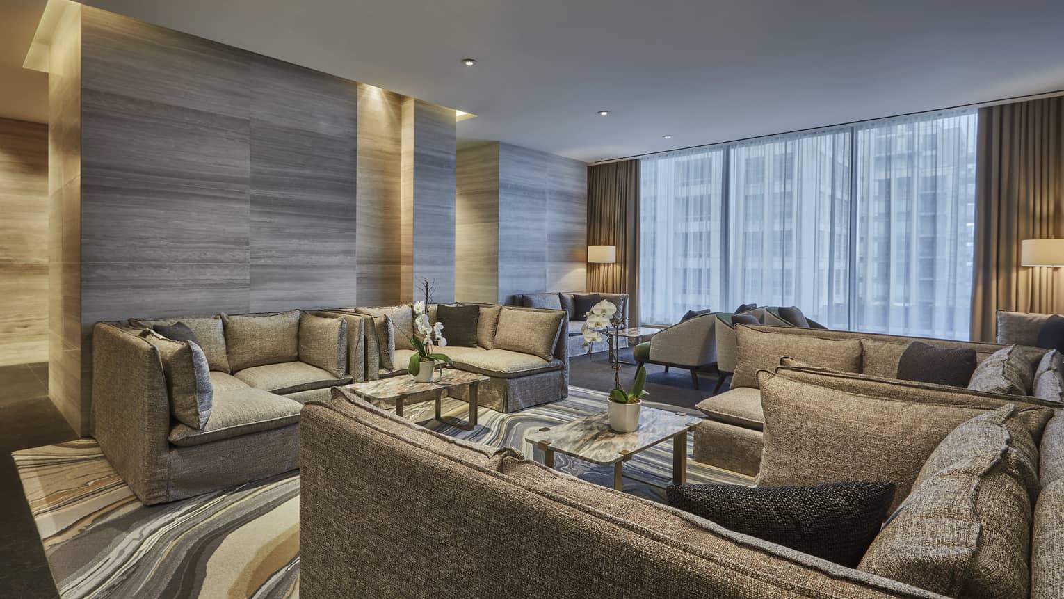 A spacious seating area featuring several L-shaped couches surrounded a glass table. 
