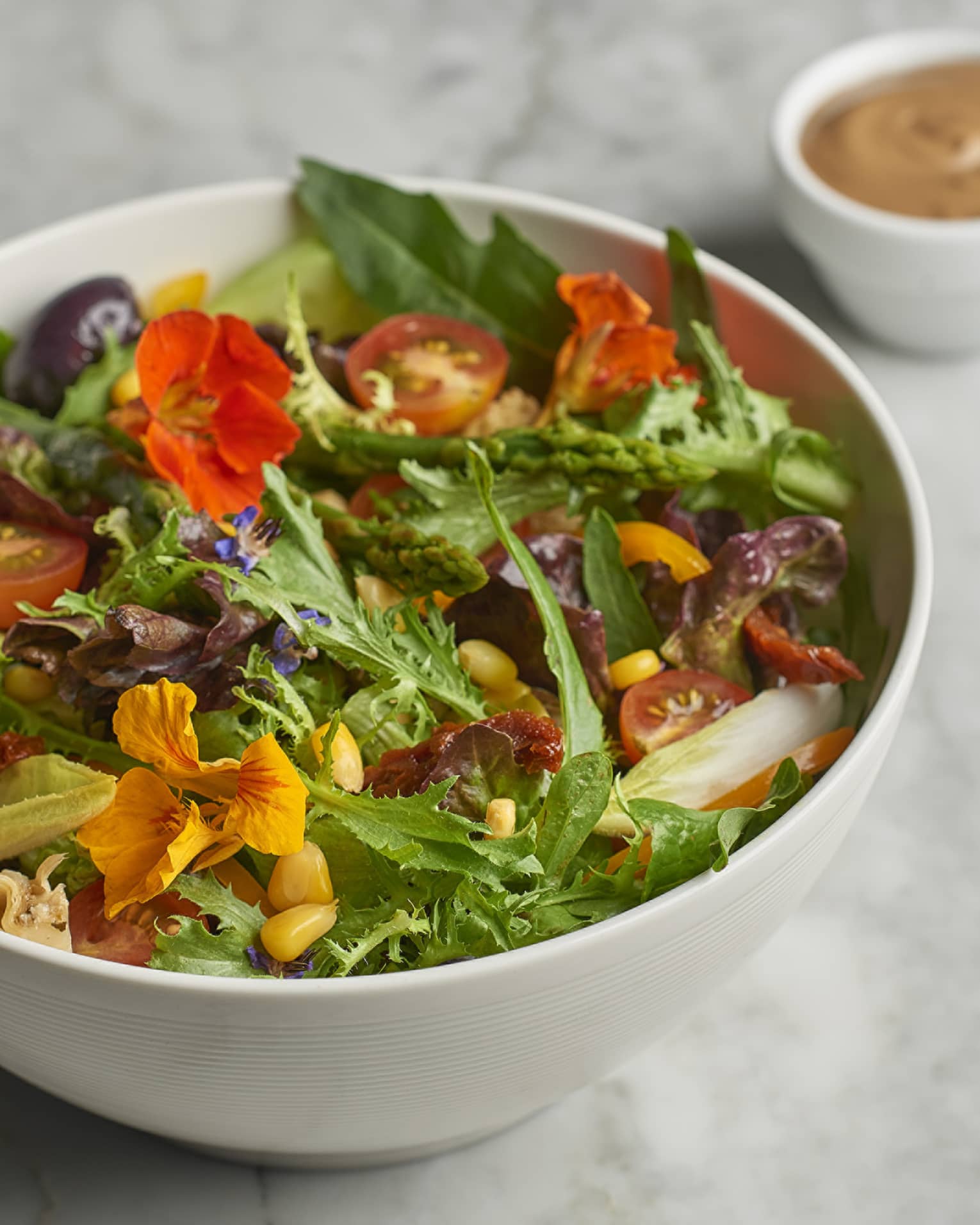Close-up of fresh organic salad with green lettuce, edible flowers, corn kernels, cherry tomatoes