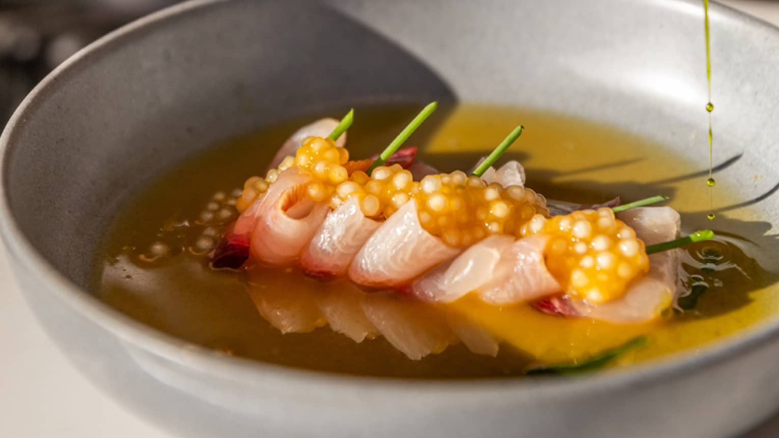 A person eating a bowl of tuna crudo