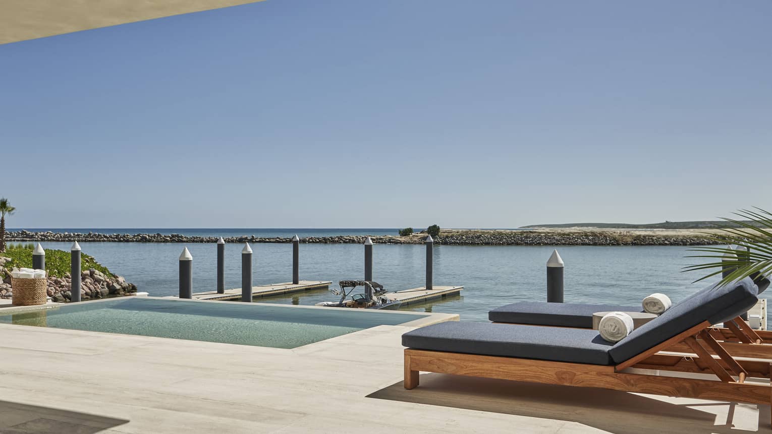 Modern terrace with teak lounge chairs and water view with boat slip