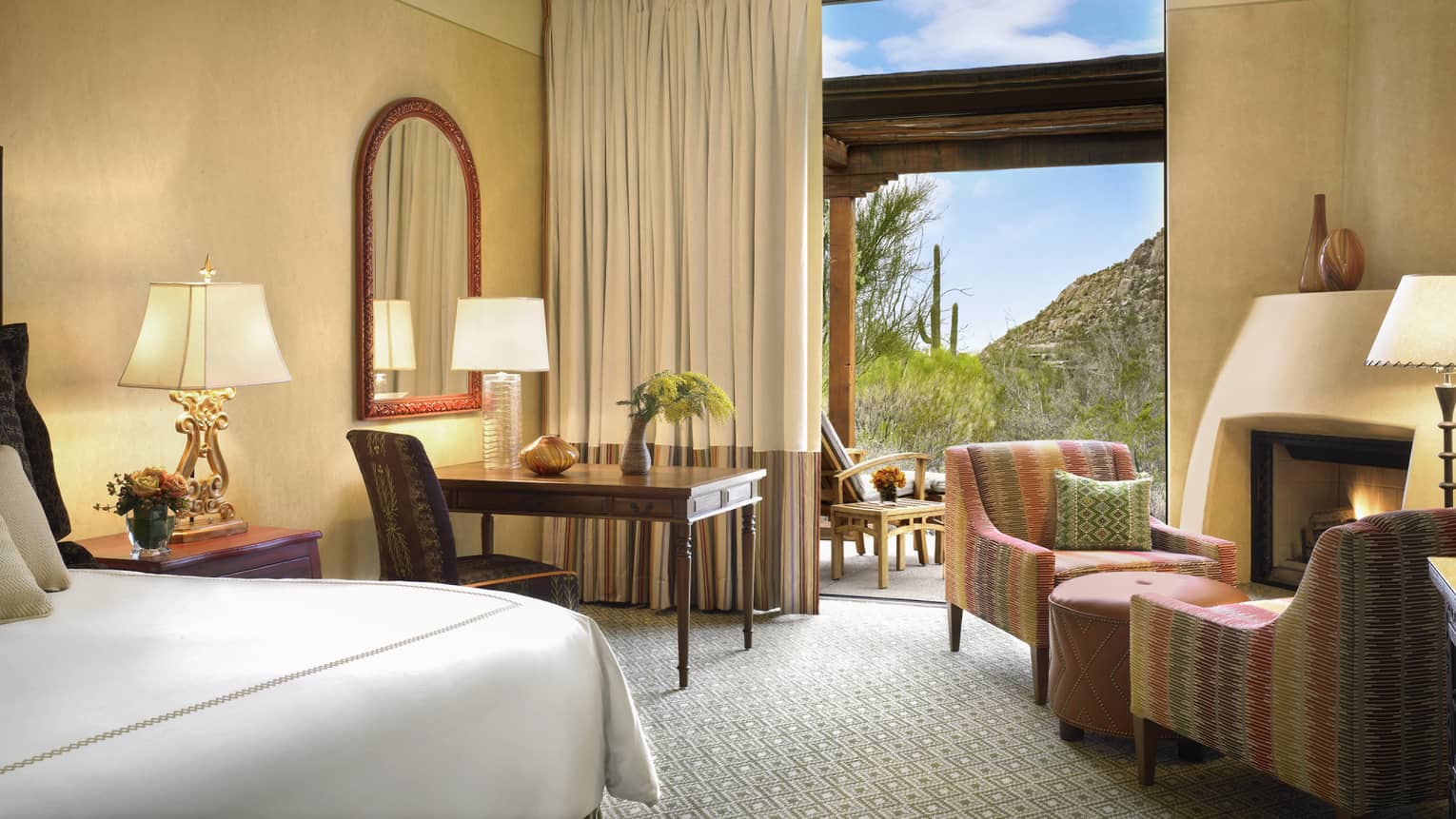 Premier Casita Room corner of bed, desk, armchairs by gas fireplace, mountain views through open balcony door