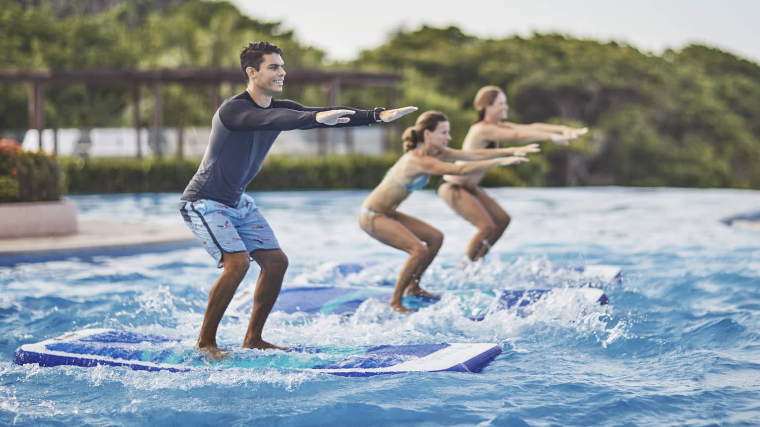 Two guests being instructed how to stand up on surf boards