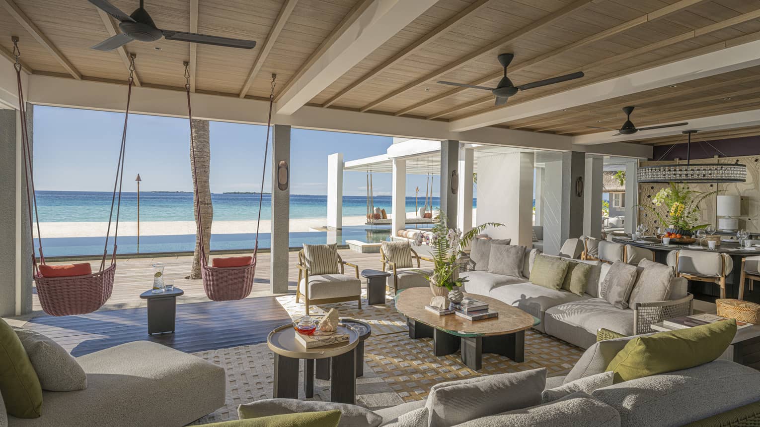 Large living room of private estate opening to a beachfront pool terrace with two hanging chairs