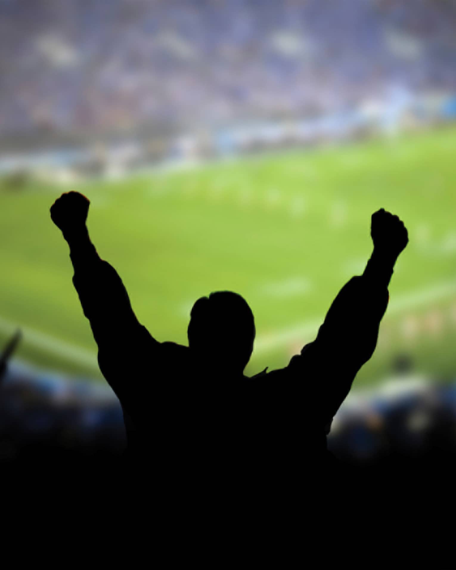 A silhouette of a person cheering at a football stadium.