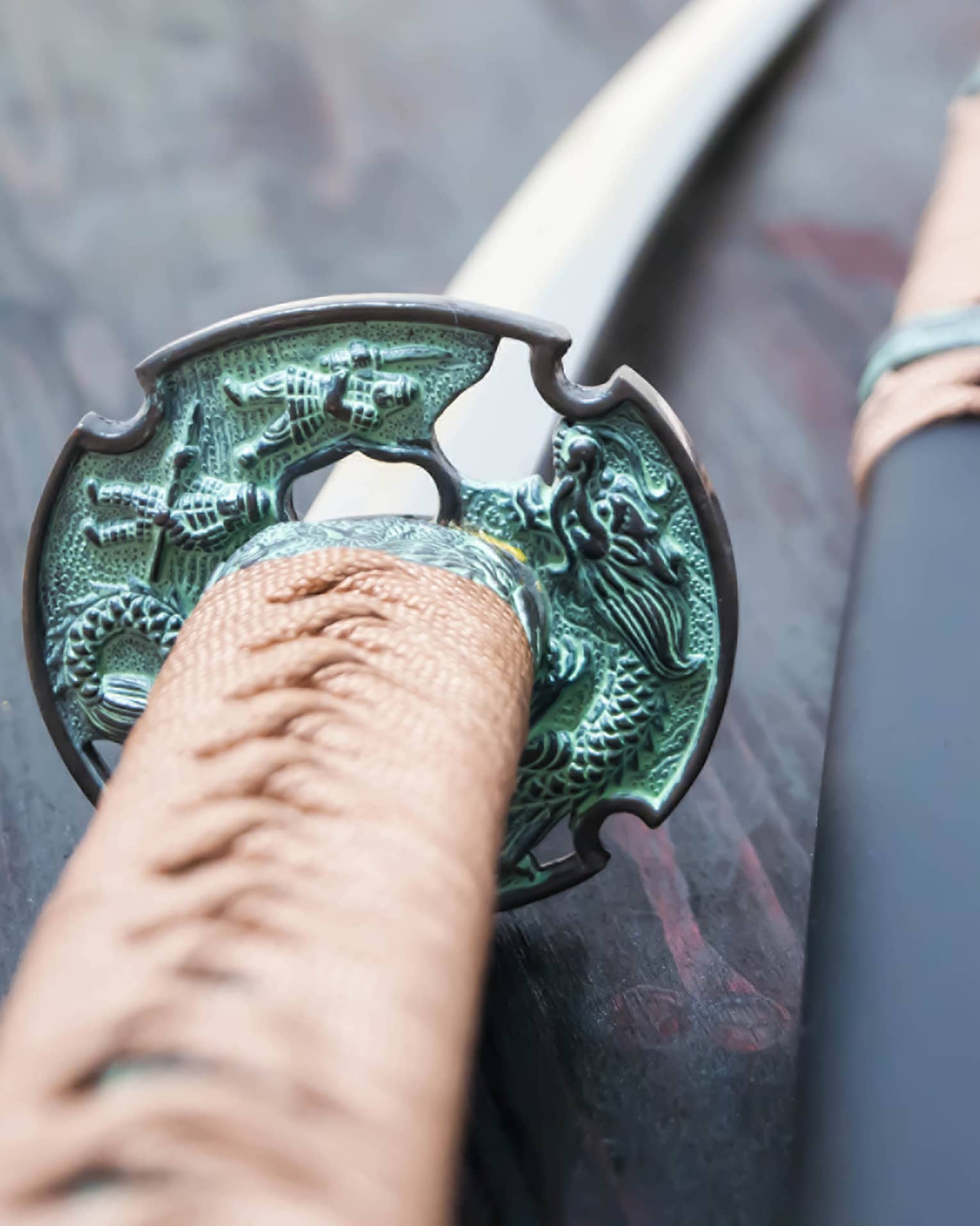 Two swords with green hilts lain on a red table.