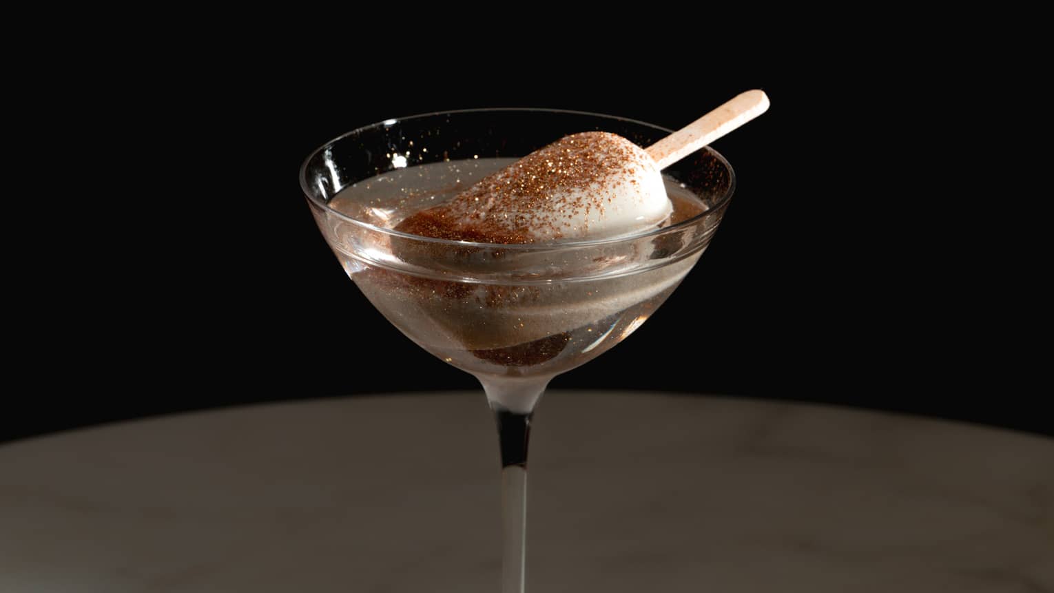 A clear drink with white garnish, in a stemmed glass