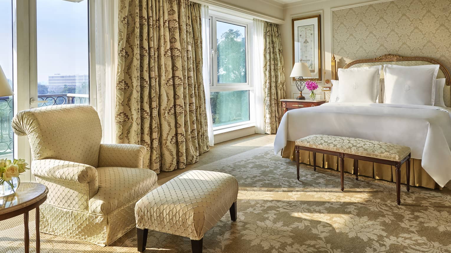 Diplomatic Suite with soft beige and cream decor, bed and club chair with ottoman
