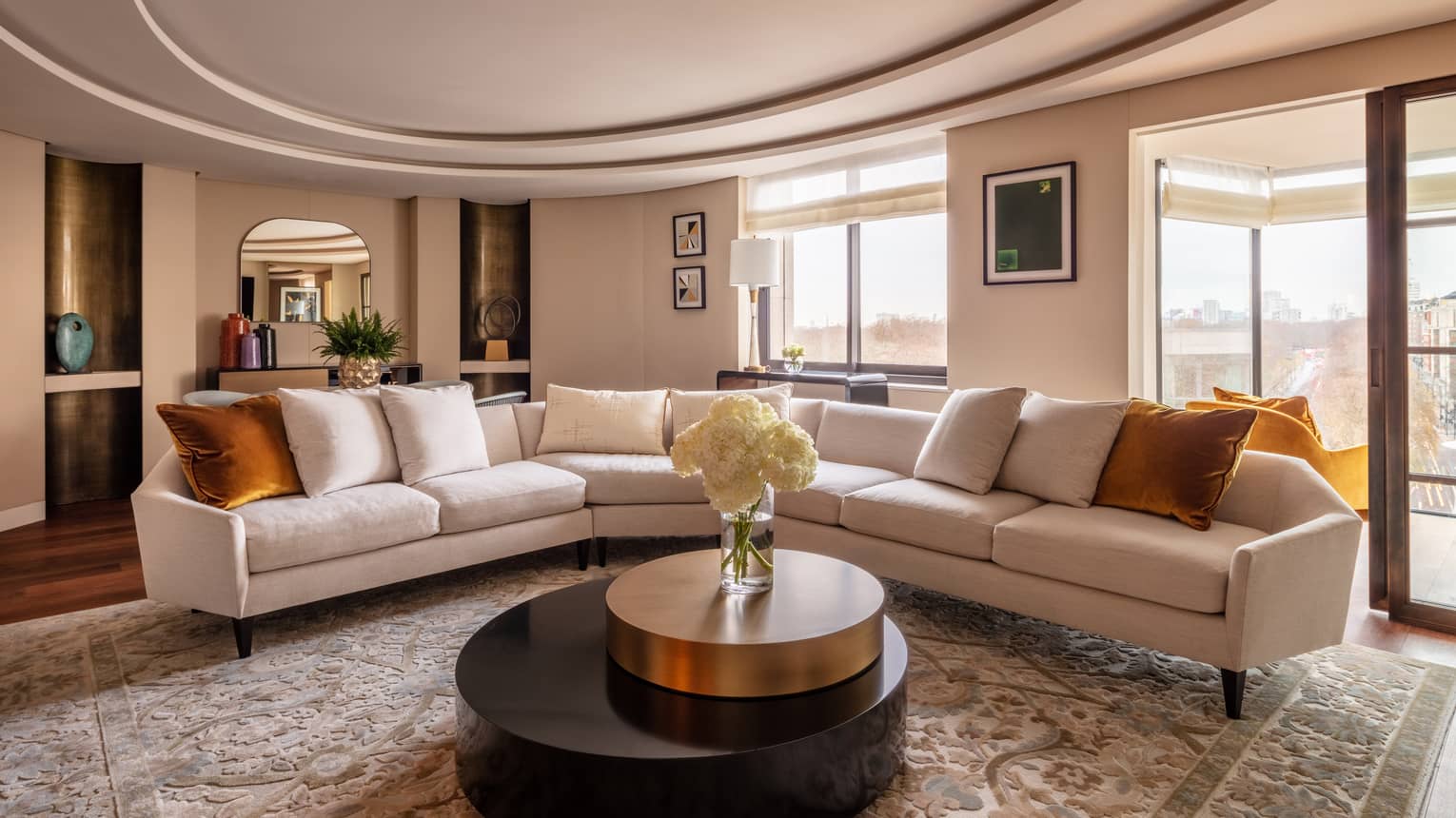 Hyde Park Suite living room with beige sectional, round coffee table with white flowers in vase