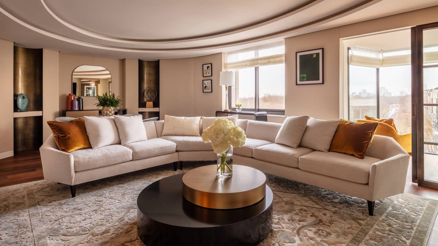 Hyde Park Suite living room with beige sectional, round coffee table with white flowers in vase