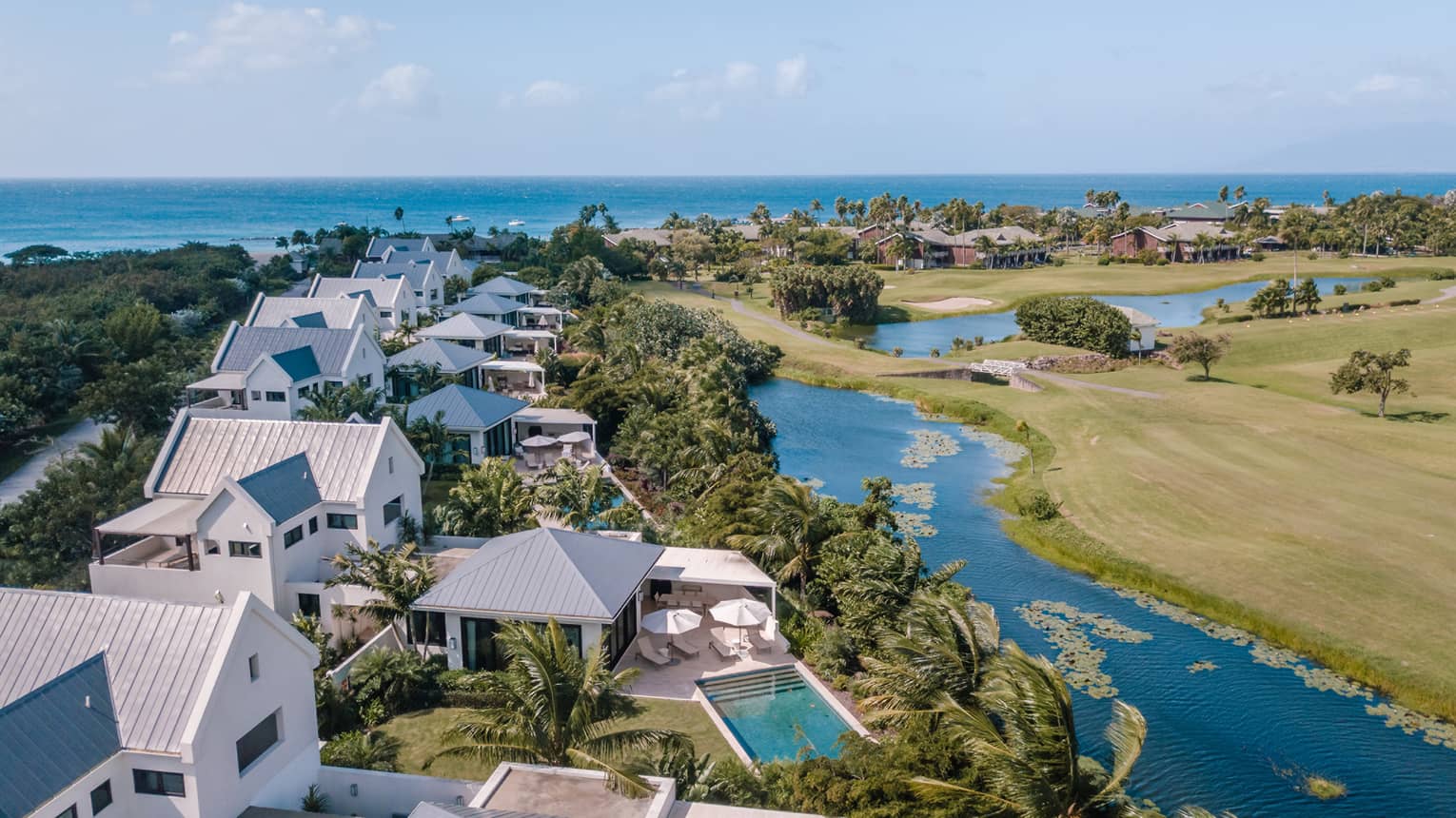 Row of white villas backing up to a small waterway in tropical environment