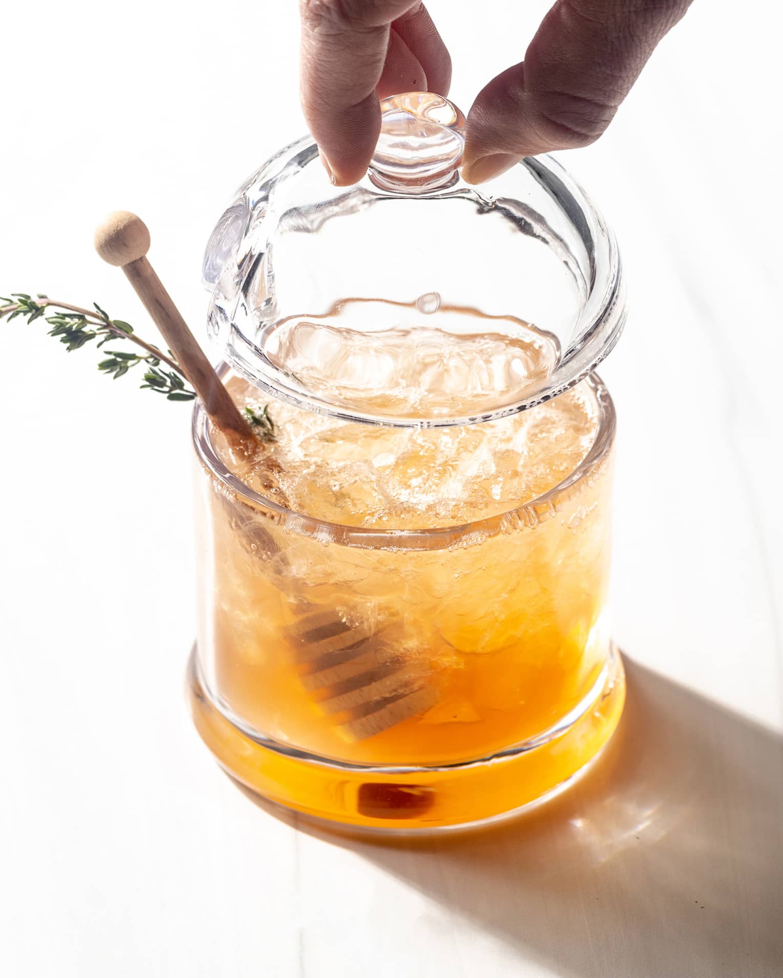 A glass of honey with an herb and wand to stir.