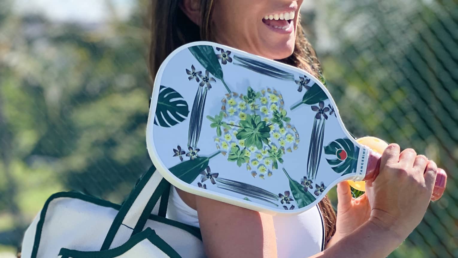 Woman holding pickleball paddle and Four Seasons bag