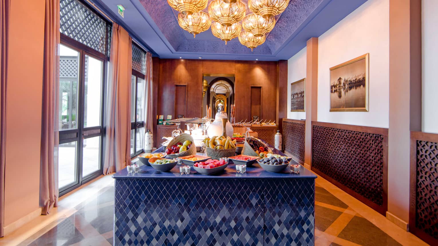 Fresh fruit on blue tile table under yellow Moroccan lamps in sunny room