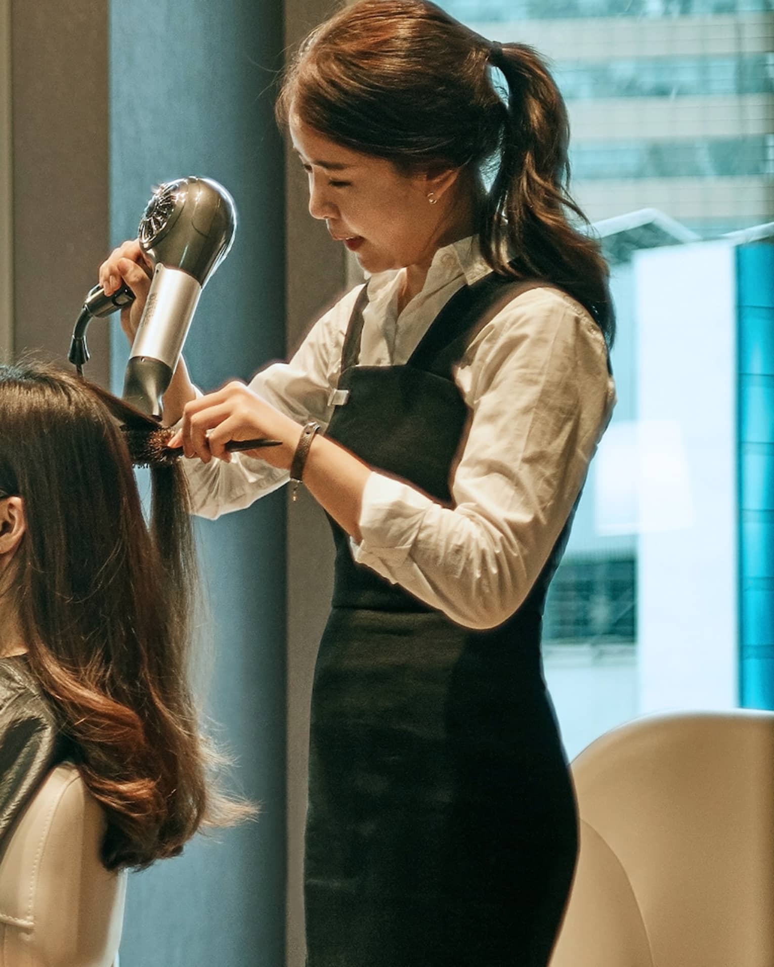 Hair stylist blow dries woman's hair in hotel salon