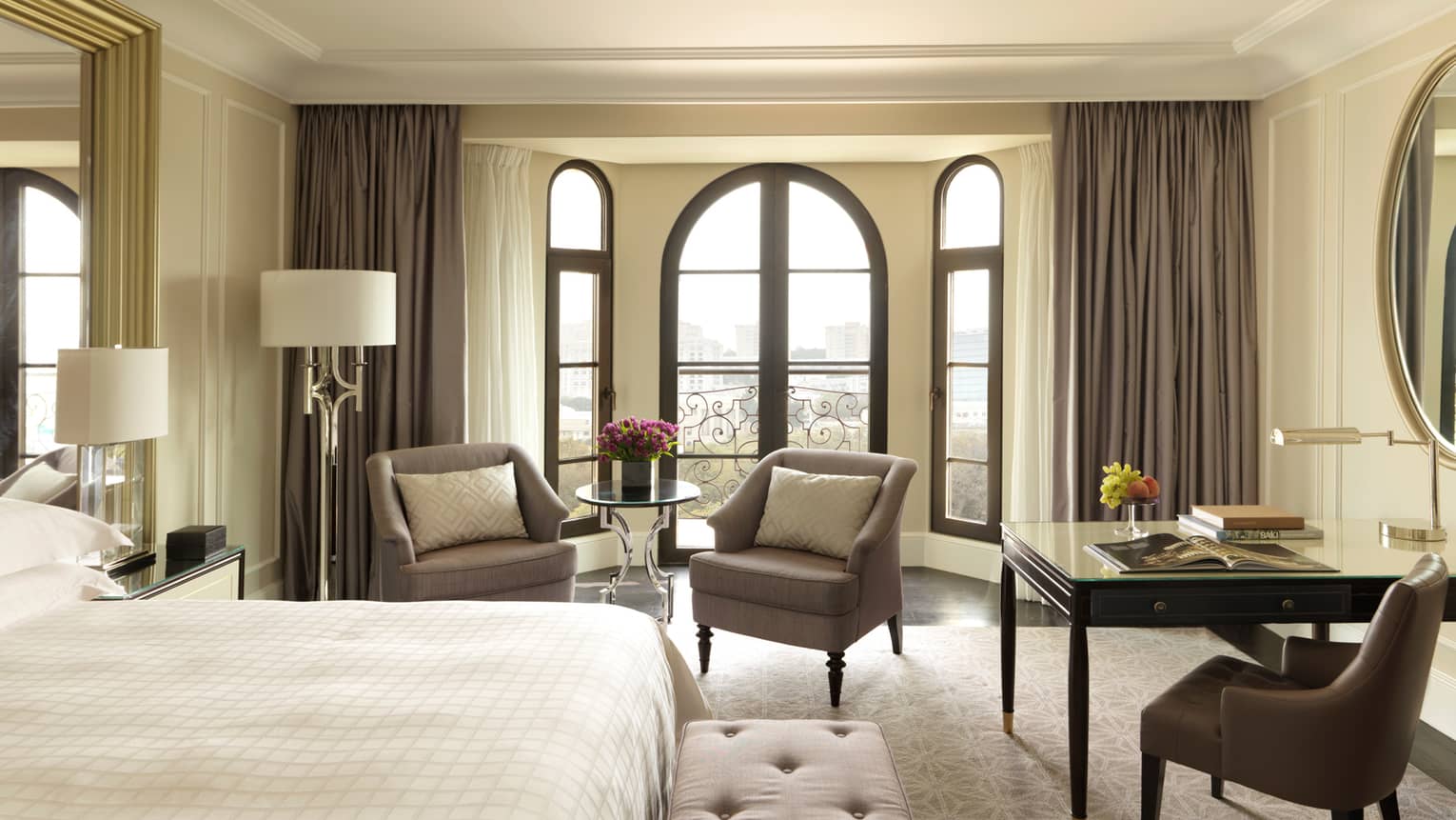 Sunny Deluxe Caspian Room hotel room with arched French doors, two armchairs, desk, bed