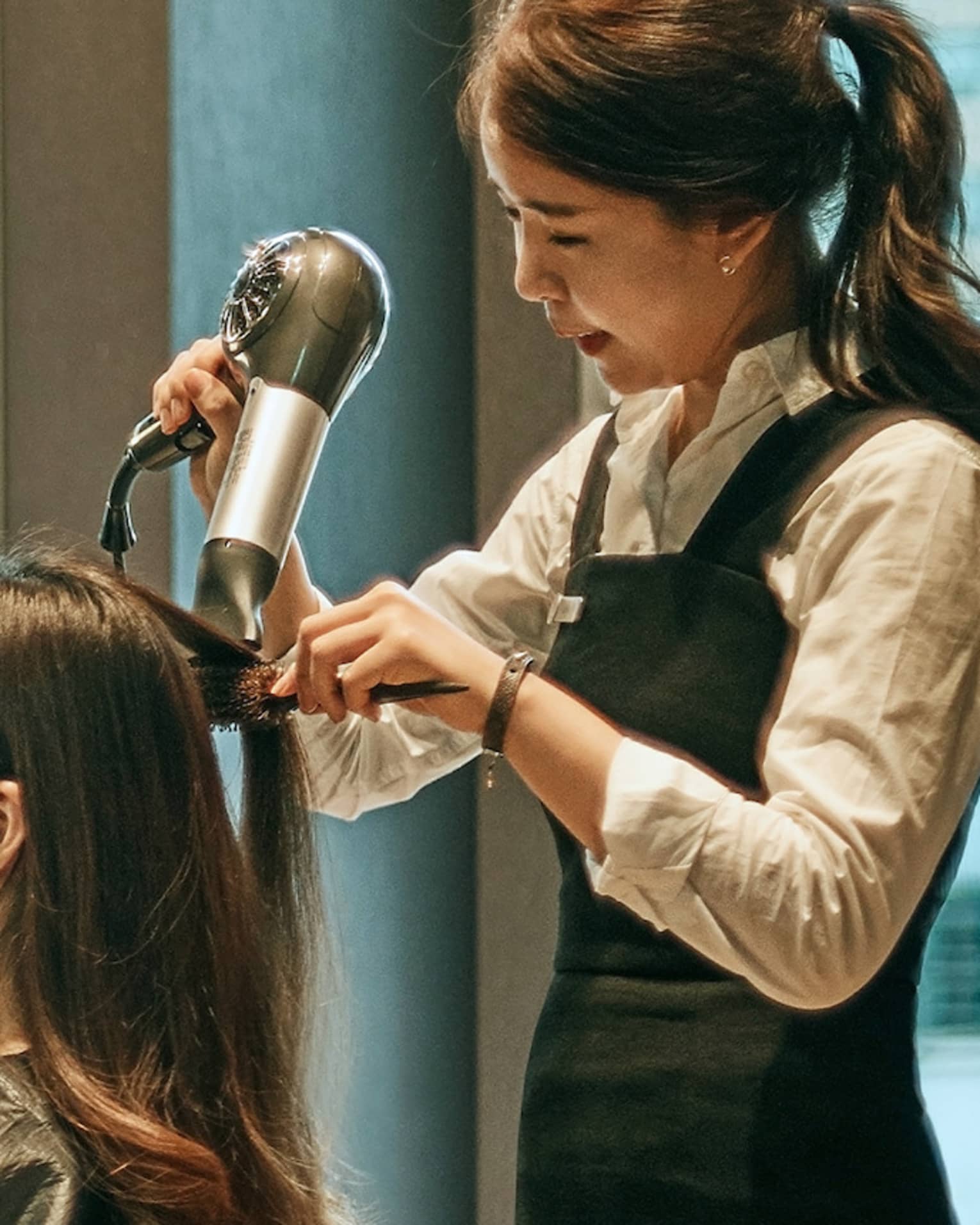 Hair stylist blow dries woman's hair in hotel salon