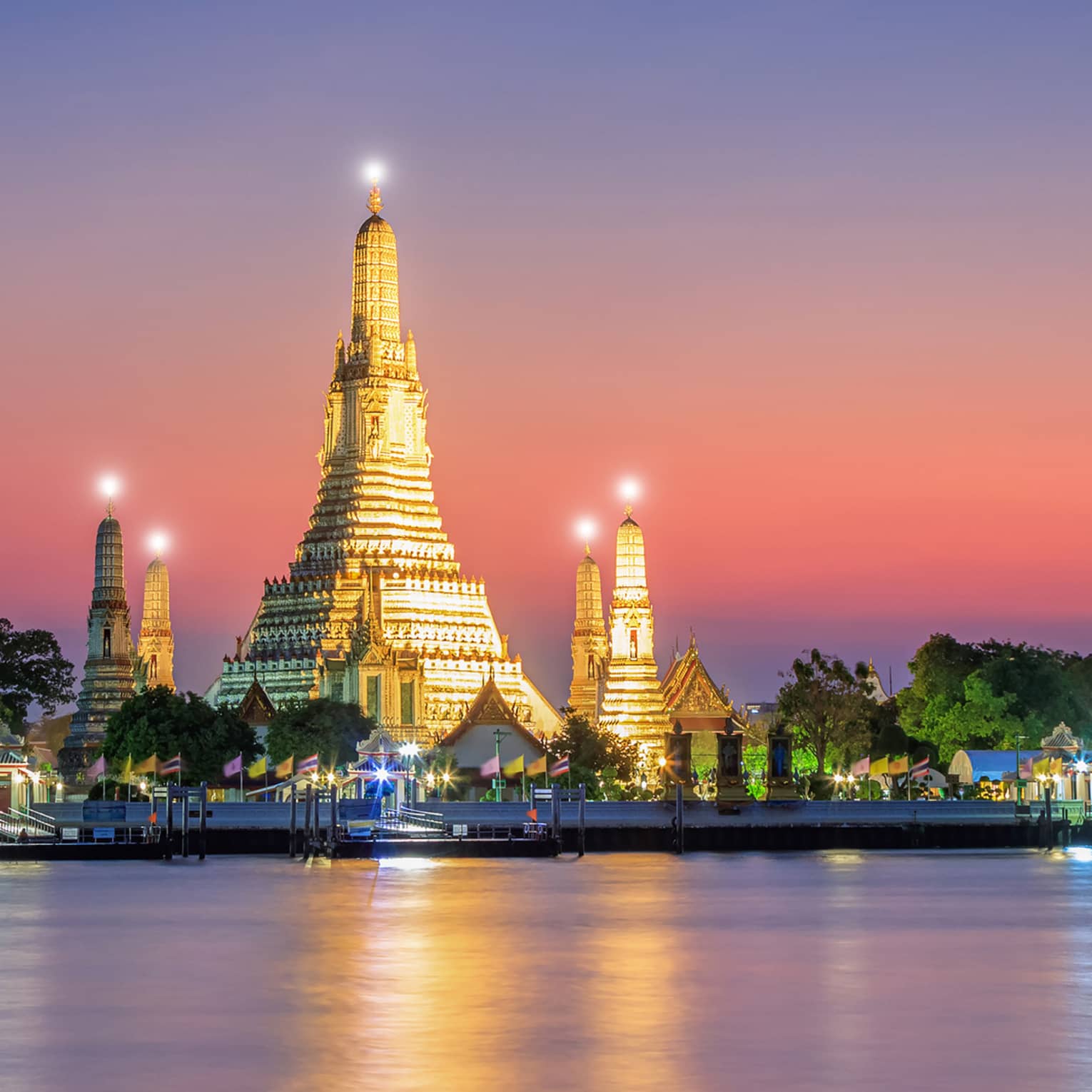 A large structure covered in lights on the shore of water.