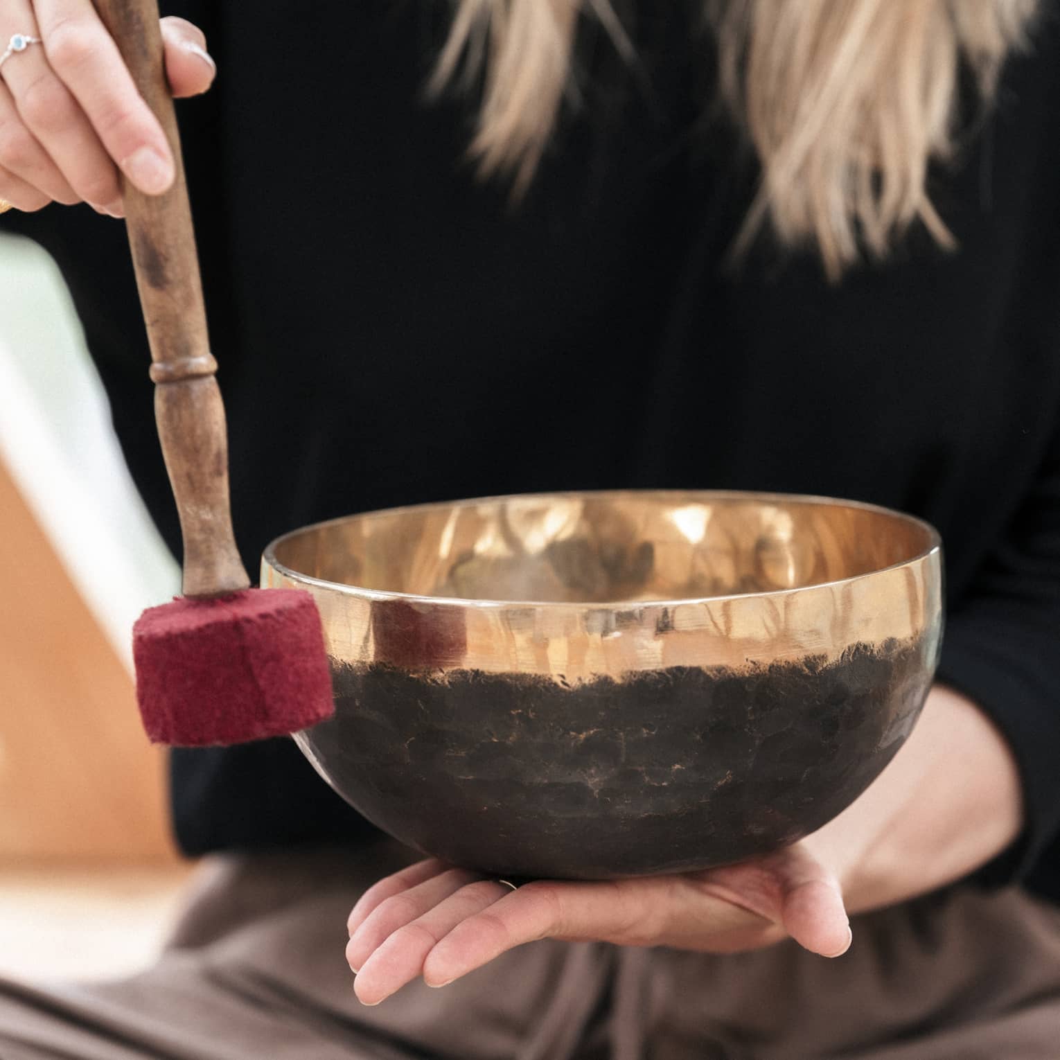 A person holding a Tibetan bowl and mallet