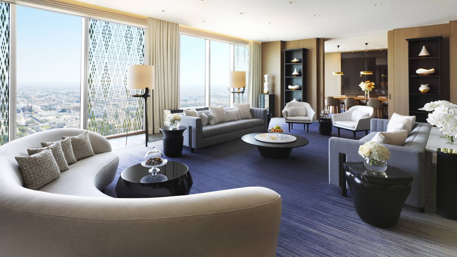State Suite modern curved sofa in front of wall of windows, seating area