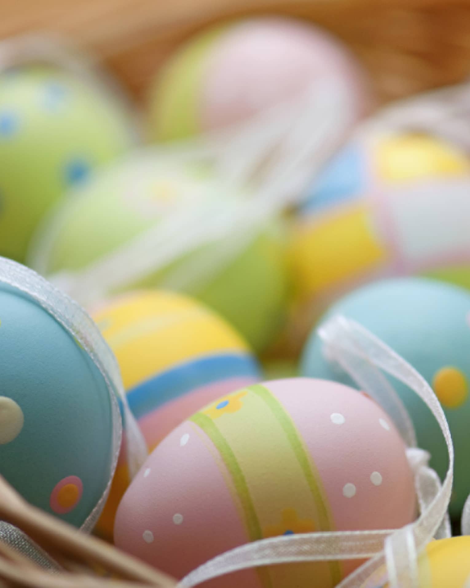 A basket of blue, pink, green and yellow colourful Easter eggs.