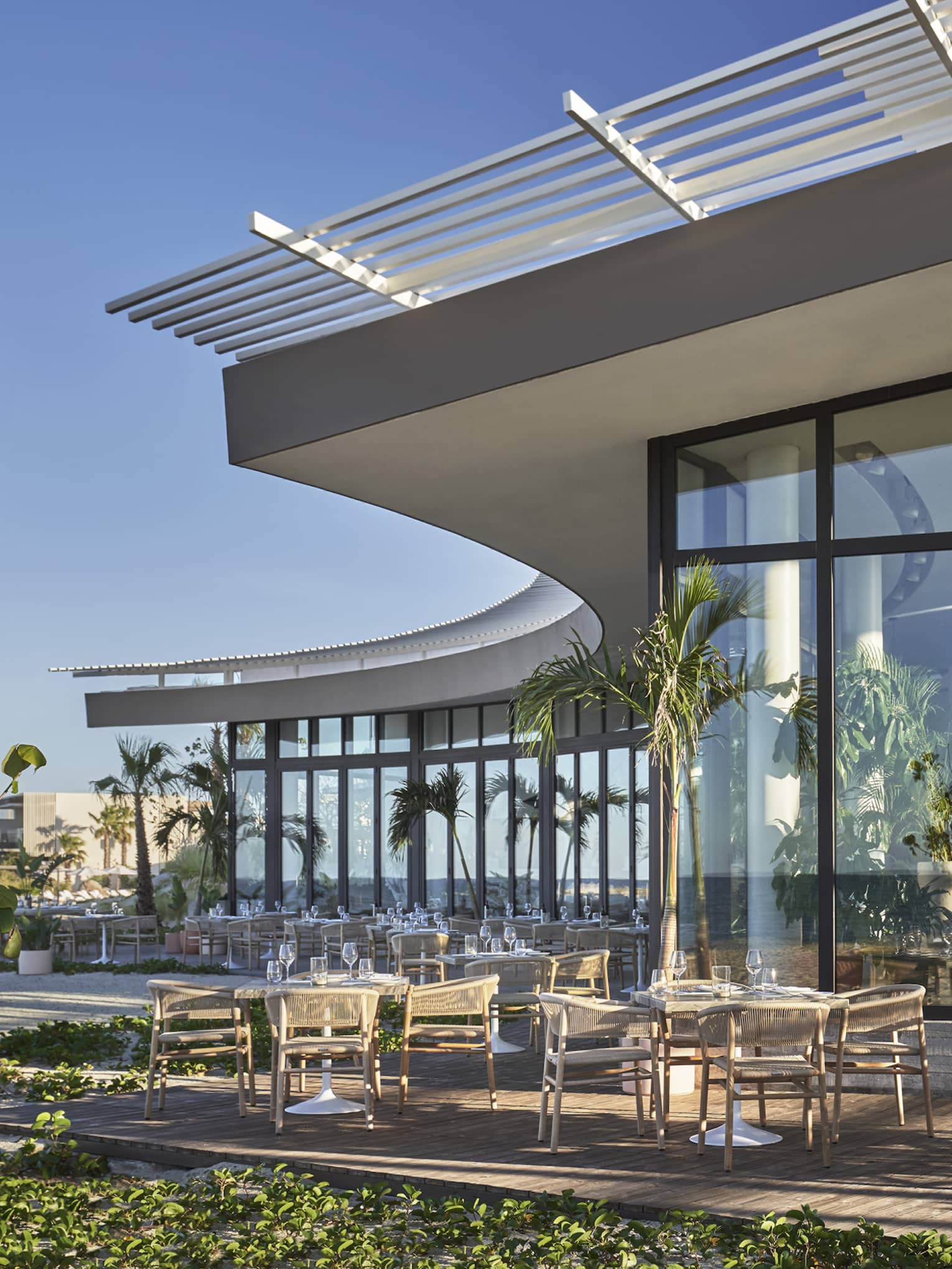A large dining outlet with floor to ceiling windows with tables and plants outside.