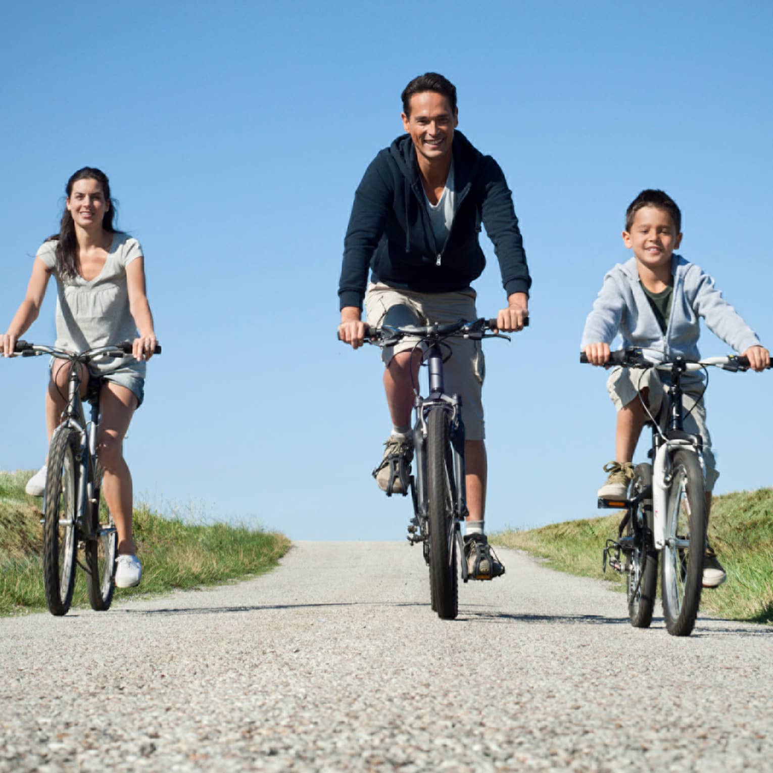 Family of three cycling on countryside pebble path