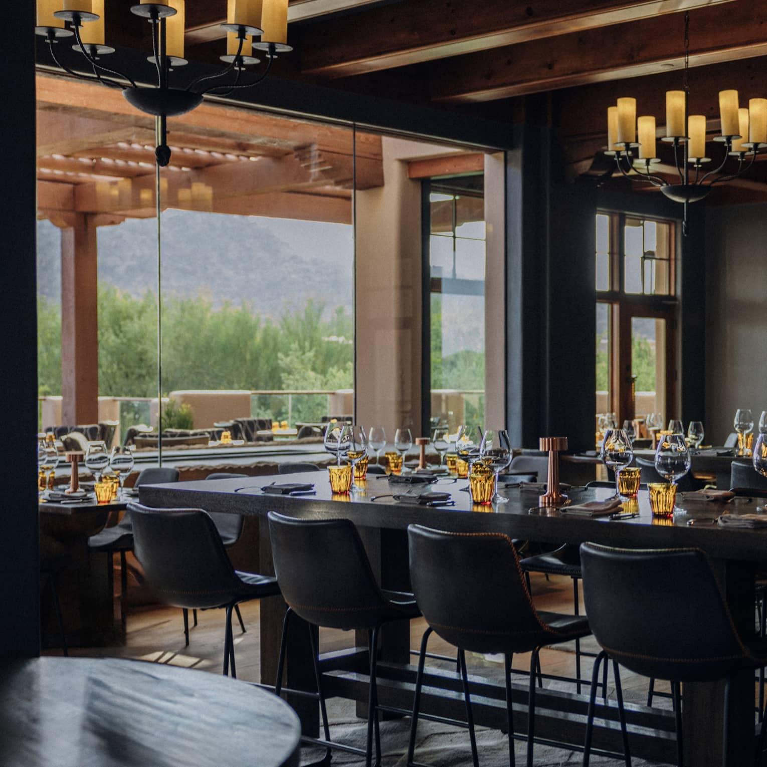 Dining room with multiple chandeliers and tables with candles.
