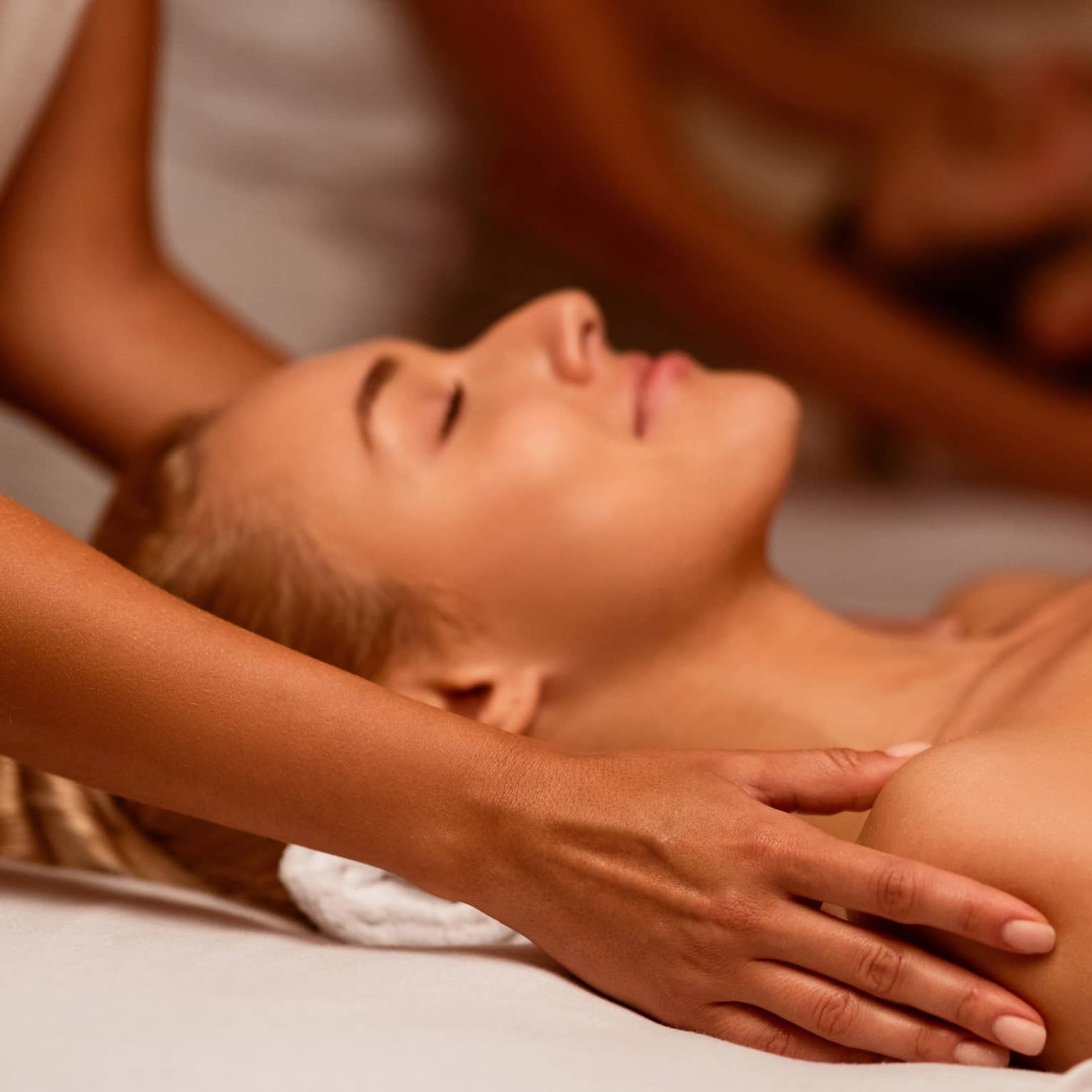 Two spa therapists perform a couples' massage