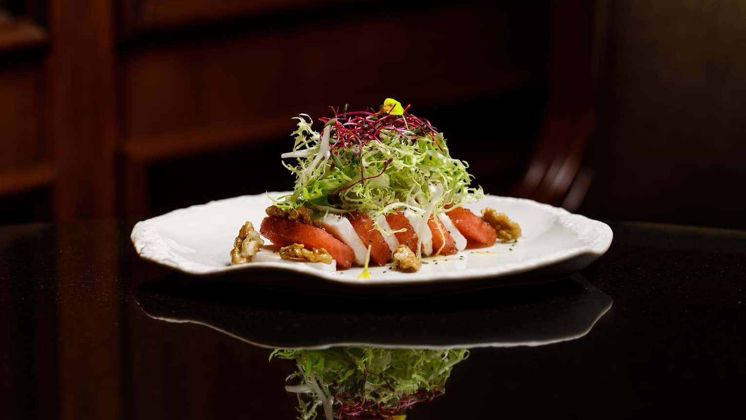 Slices of watermelon and feta topped with lettuce on a white plate
