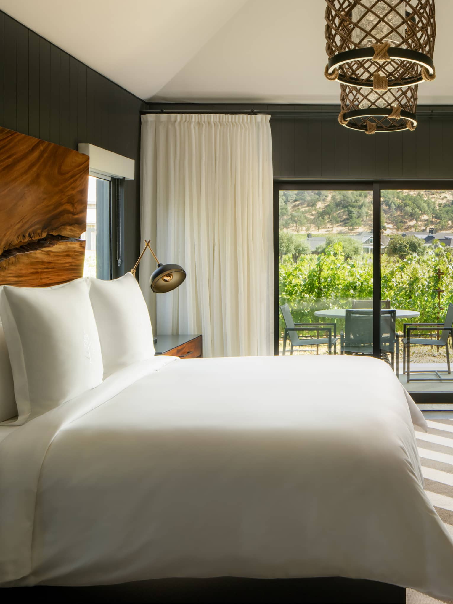 Contemporary bedroom with king bed, diagonal striped rug, natural wood headboard and walk-out terrace