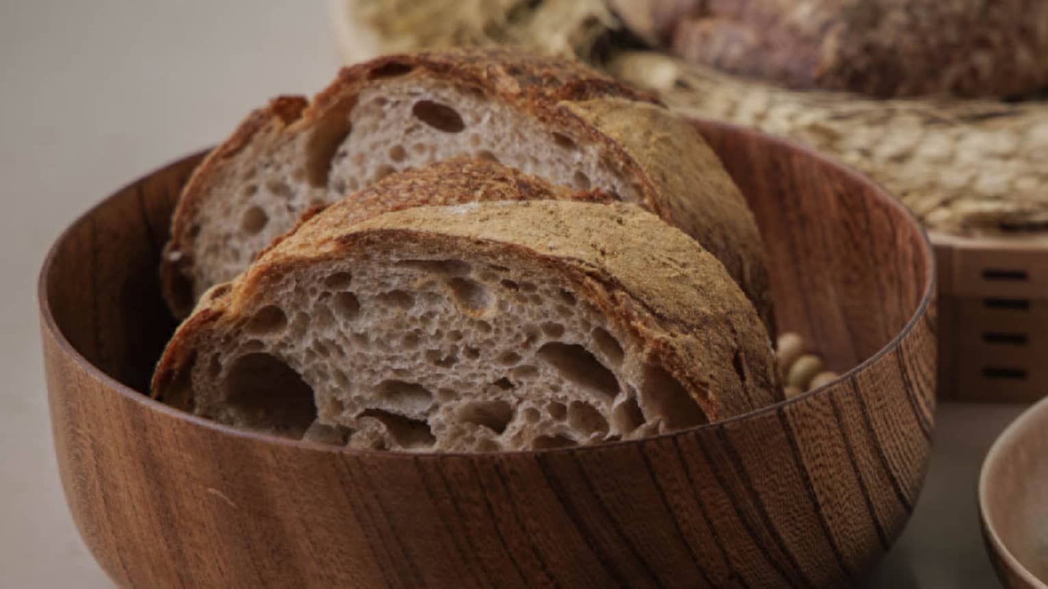 Sliced bread served in a wooden bowl with butter