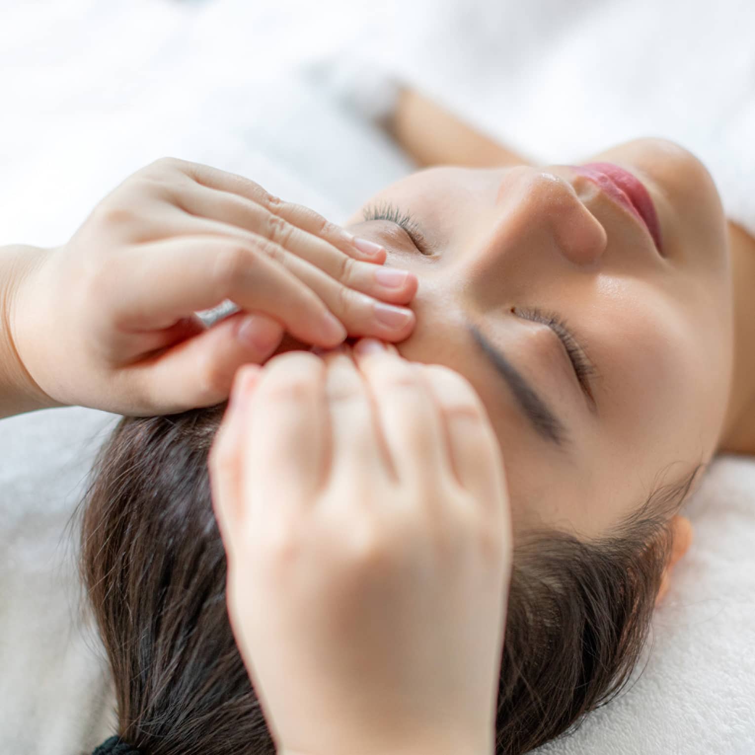 A woman getting a facial massage in a spa.