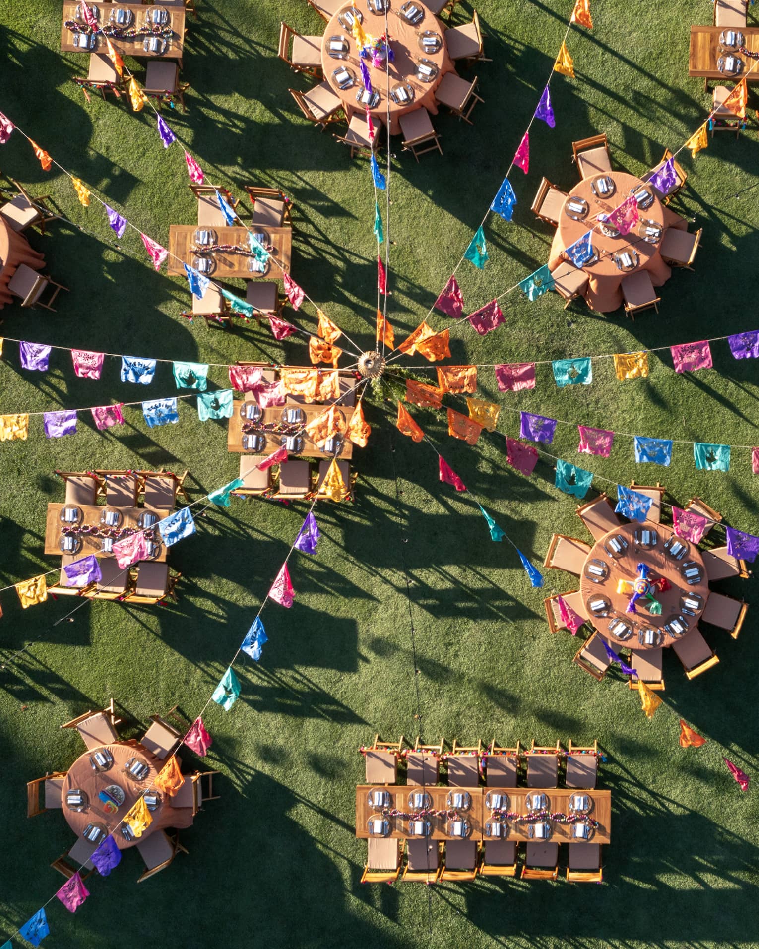 Many dining tables and chairs set up with colourful streamer decorations above it.