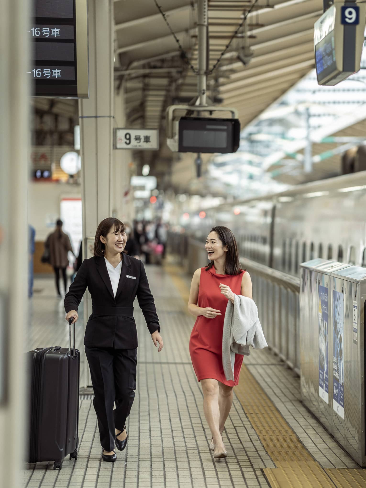 Train station greeter walks with female guest along the train platform