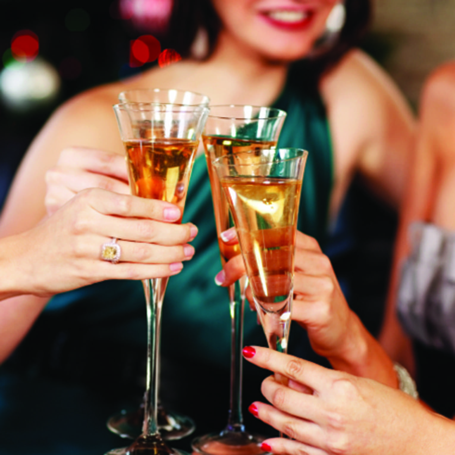 Close-up of women in evening gowns toasting with glasses of Champagne