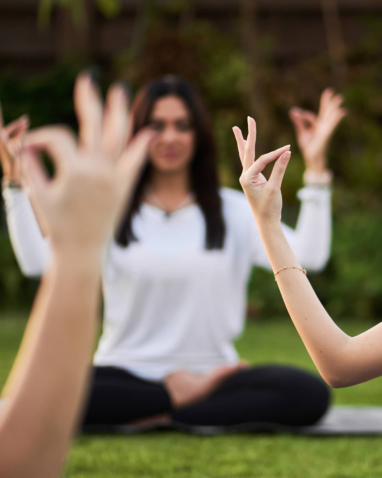 Guests doing yoga outdoors on yoga mats with trees in the background